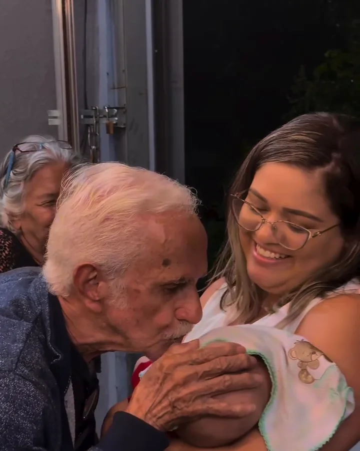 Senhor beijando com carinho um bebê no colo da mãe