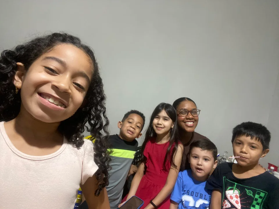 Menina sorrindo em uma selfie com outras crianças e a professora do Ministério Infantil