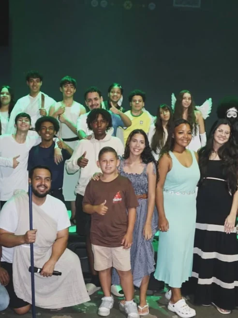 Foto em grupo dos jovens da ICMR, sorrindo juntos no palco depois de um culto