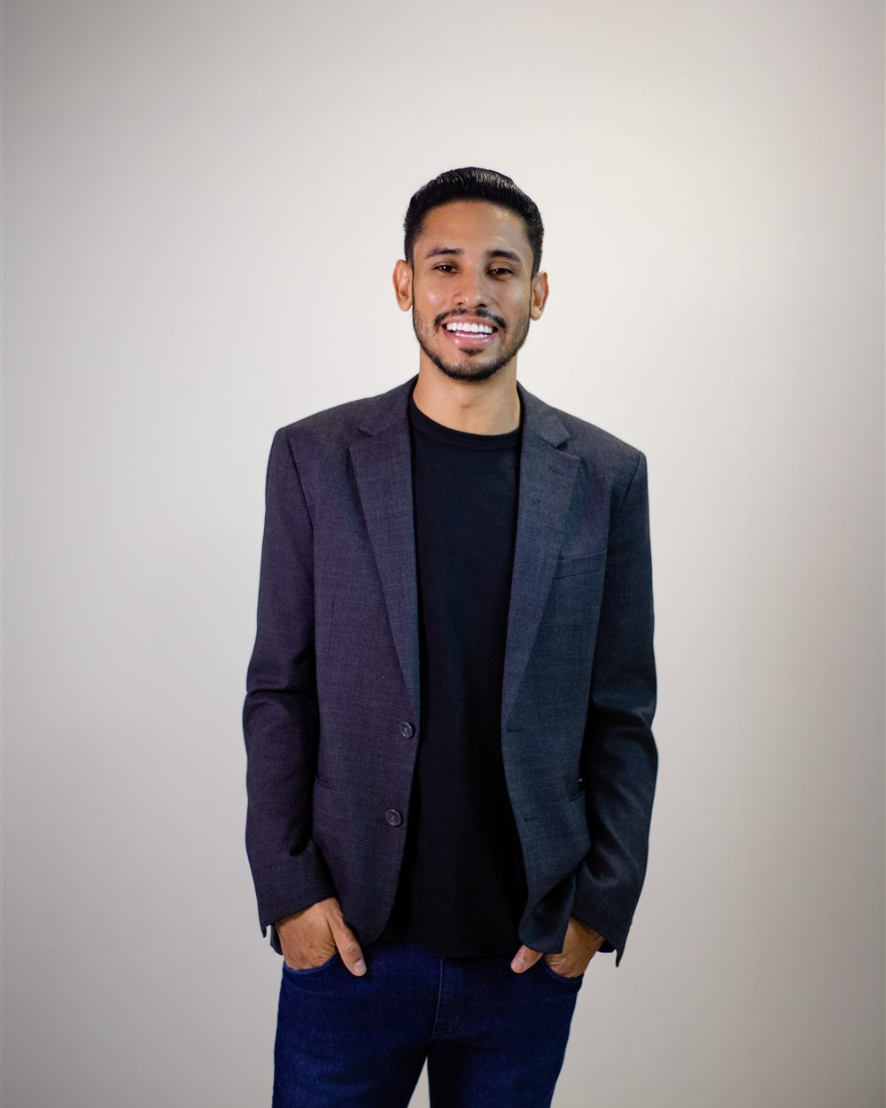 Pastor Kaic Renúncia sorrindo, de blazer cinza e camiseta preta